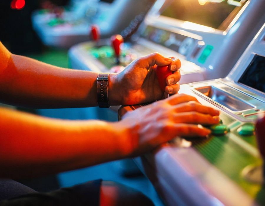 Detail on hands playing with joystick on old vintage arcade game in a dark room for playing video games